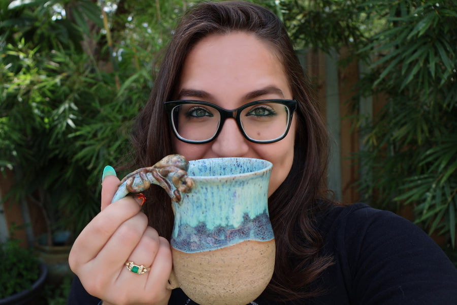 The maker holding a turquoise octopus mug in the garden