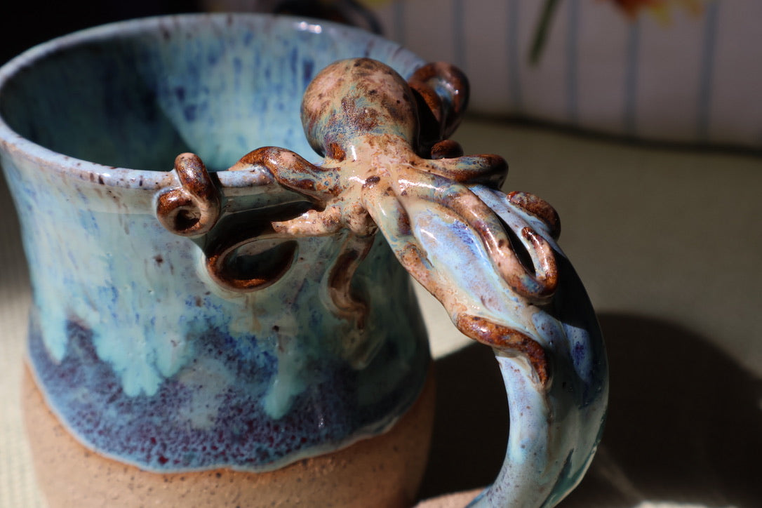 Close-up of a sculpted octopus climbing the handle of a turquoise glazed mug