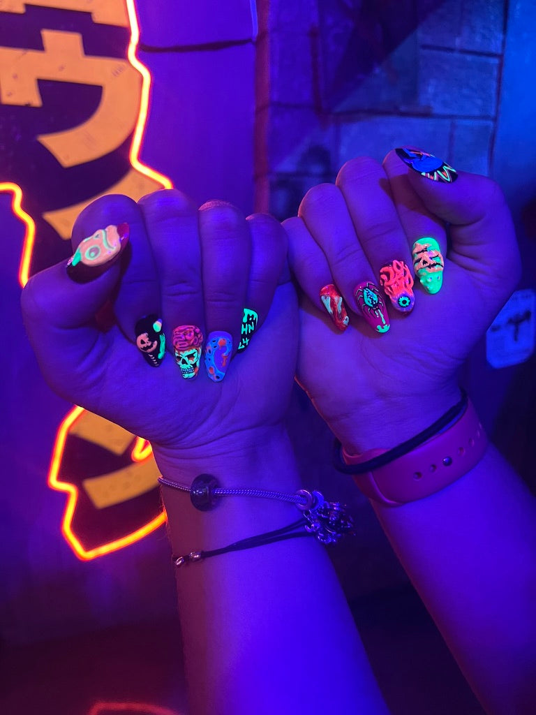 Two hands wearing detailed hand-painted press-on nails at sunset