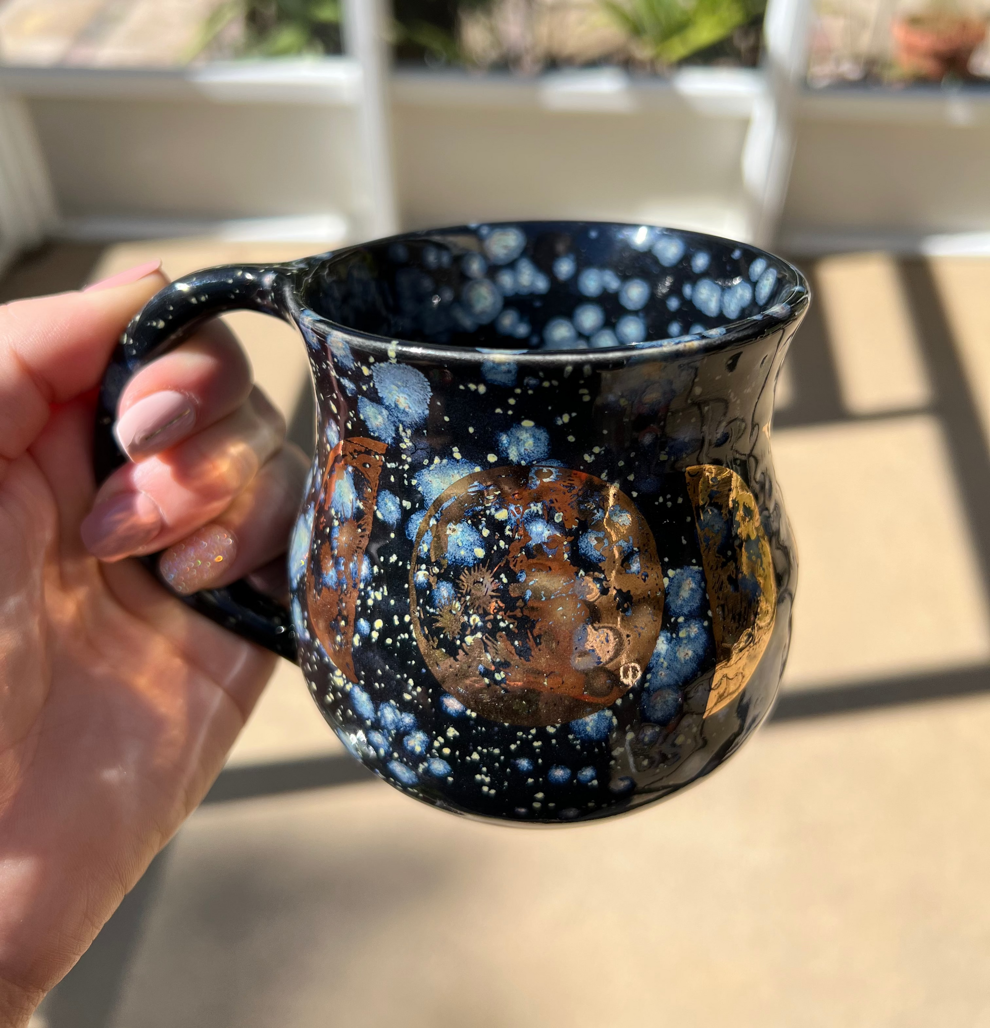 A black speckled mug with gold and copper moons